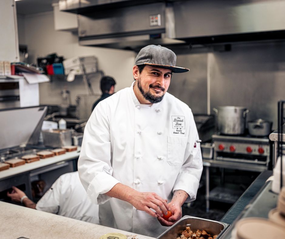 Chef in kitchen wearing white chef coat and prepping food