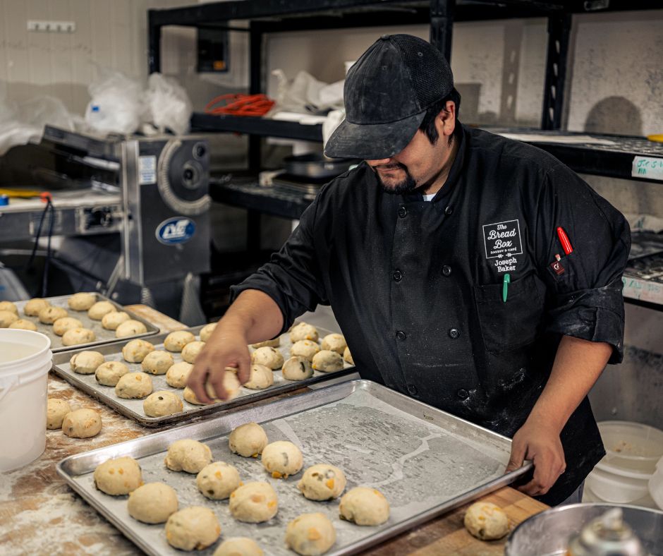 kitchen staff loading baking tray with dinner rolls